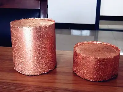 Two cylindrical copper granule briquettes of different sizes