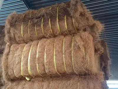 Palm fibre bales stacked under a warehouse roof