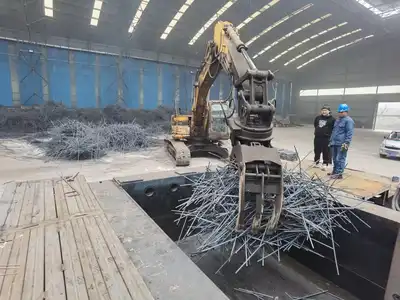 Excavator loading long steel bars into a baler