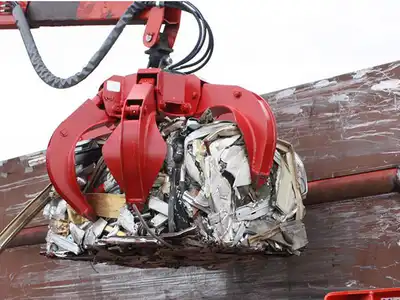 Grapple handling a dense compressed waste car bale