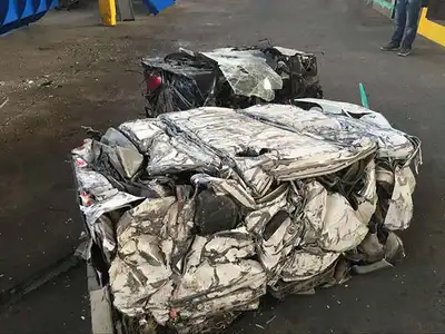 Finished waste car bale beside a dedicated car baler