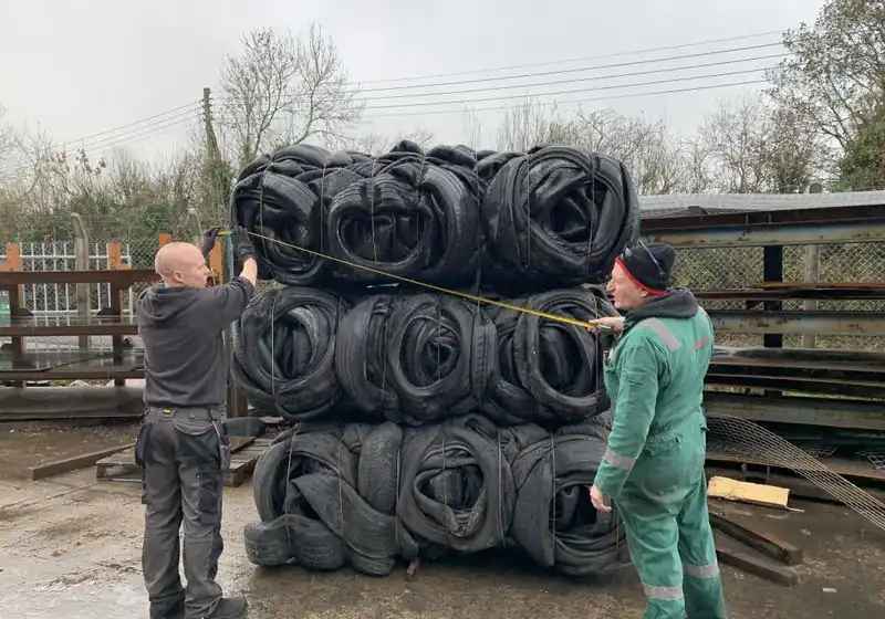 People measuring the dimensions of retained tire bales