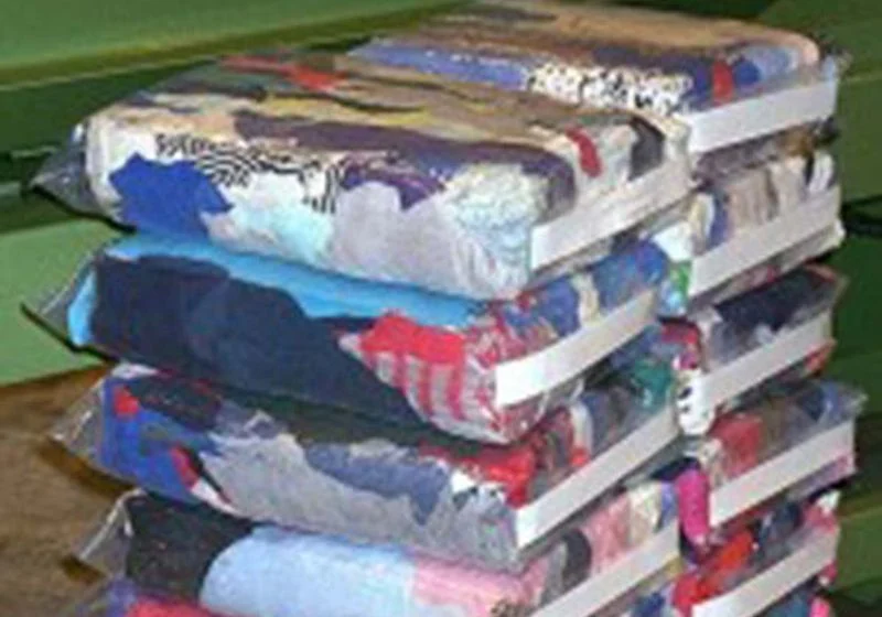 Bagged and strapped mixed-colour textile packages arranged in a small stack