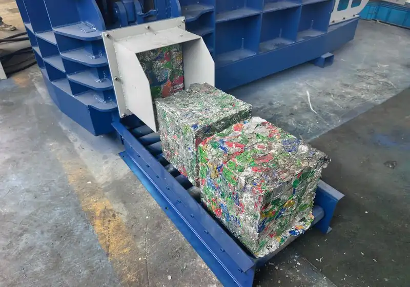 Compressed aluminium beverage can bales on a roller conveyor beside the shear baler