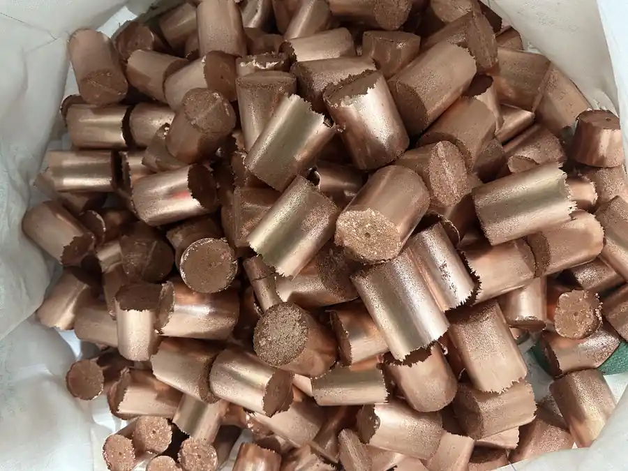 Compact cylindrical copper granule briquettes collected in a bag