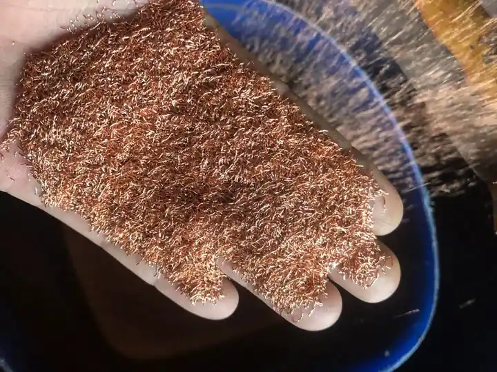 Hand holding loose copper granules before briquetting