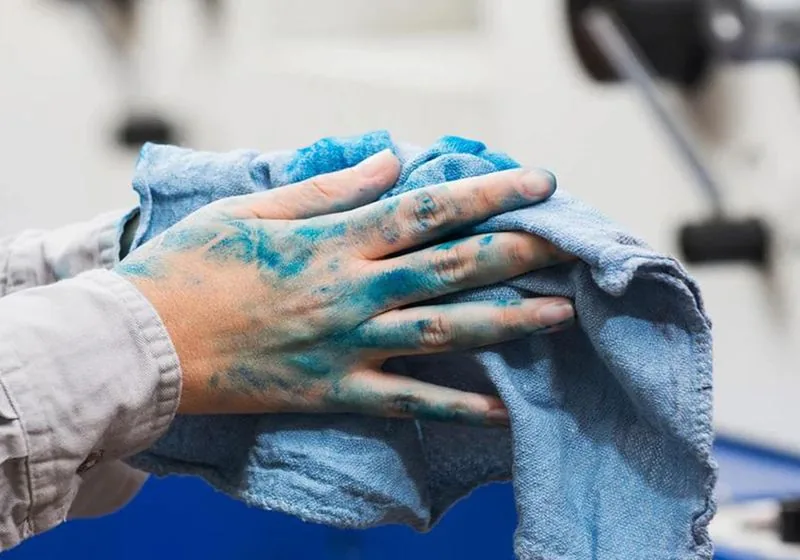 Industrial wiping cloth being used to clean a workshop surface