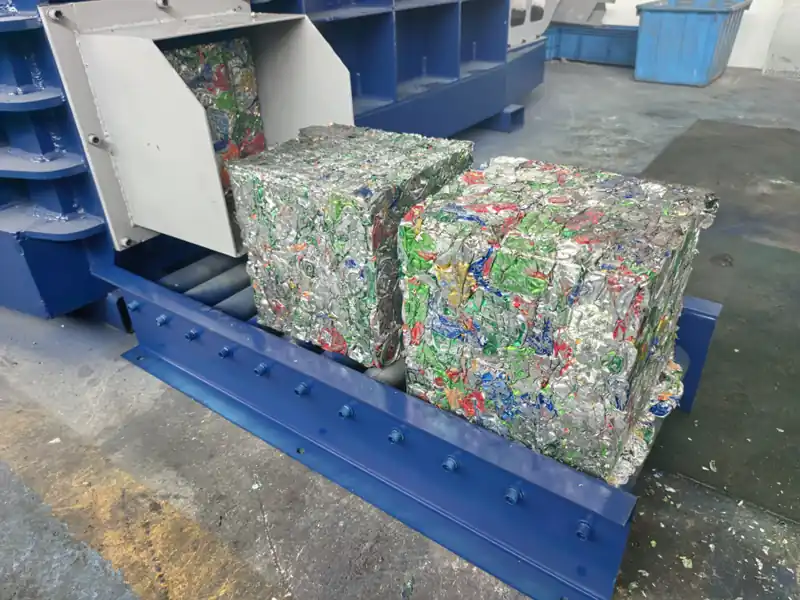 Two compact aluminium can bales on the baler discharge chute