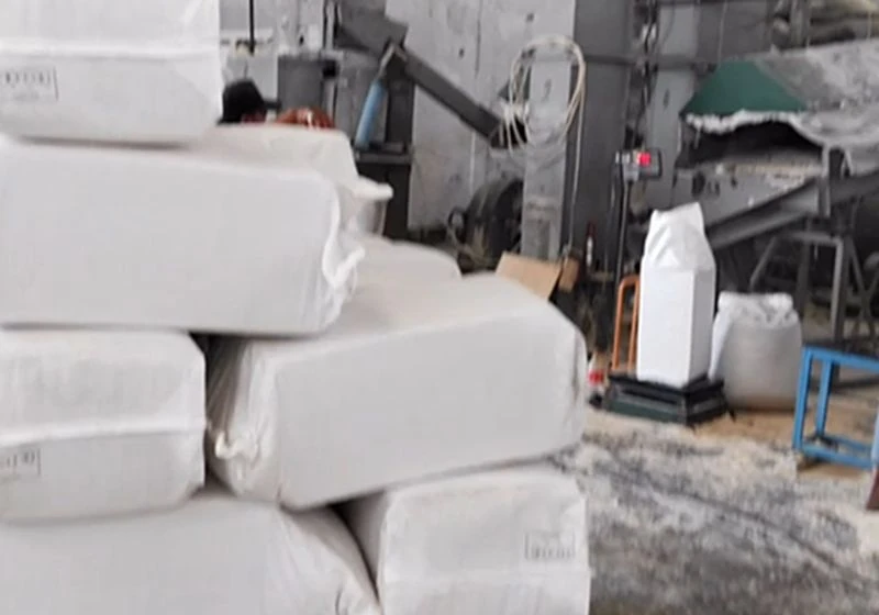 White bagged corncob packages stacked beside production equipment