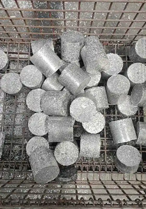 Cylindrical aluminium briquettes collected in a metal bin