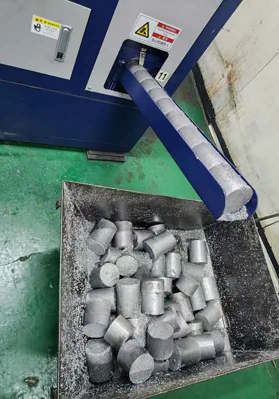 Aluminium chip briquettes collected below the press discharge chute