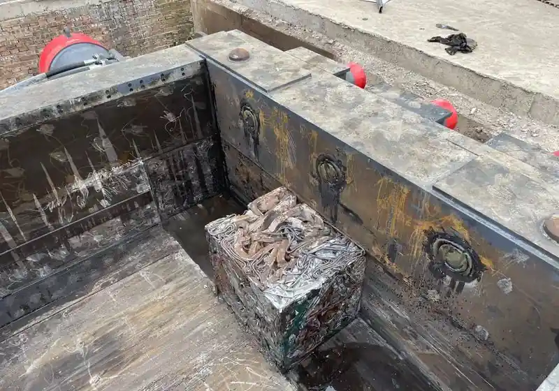 Compressed ferrous scrap bale inside a heavy-duty metal baler chamber