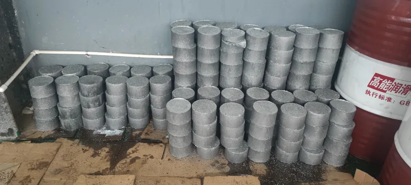 Finished aluminium chip briquettes stacked beside the press