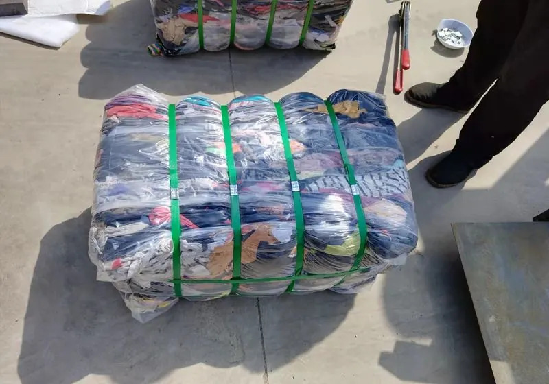 Compressed mixed-colour clothing bale secured with green straps