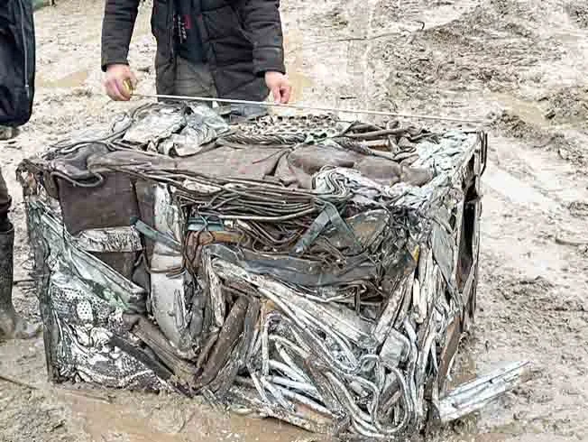 Compressed scrap-metal bale with a tape measure being held across its top